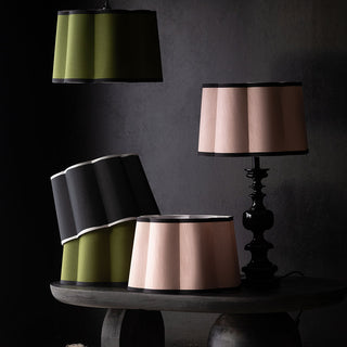 Green, black and cream scalloped lampshades on table lights, ceiling lights and a table.