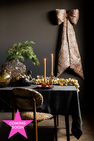 The Leopard Print Velvet Oversized Bow Decoration styled above a festive tablescape. Image shown with pink star coming soon icon. 