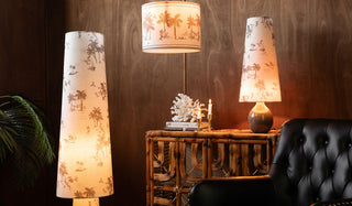 Three printed lights displayed on/around a sideboard, chair and plant, in front of a dark wall.