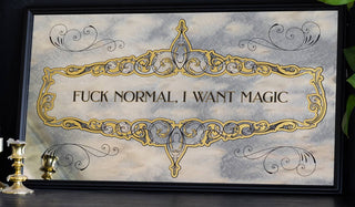 The Fuck Normal, I Want Magic Mirror displayed in front of a black wall, styled with a plant and wax-covered candlesticks.