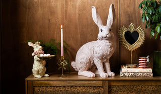 Some Easter rabbit ornaments styled on a leopard print sideboard with some plants and various accessories.