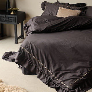 Lifestyle image of the Mega Frill Charcoal Cotton Bedding Set displayed in a bedroom surrounded by home accessories. 