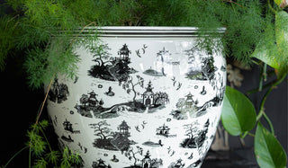 Lifestyle image of the Large Willow Toile Planter styled with plants, displayed on a black sideboard. 