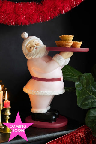 The Pink Santa Butler Christmas Decoration holding some mince pies, with a pink star that says 'coming soon' in the corner.