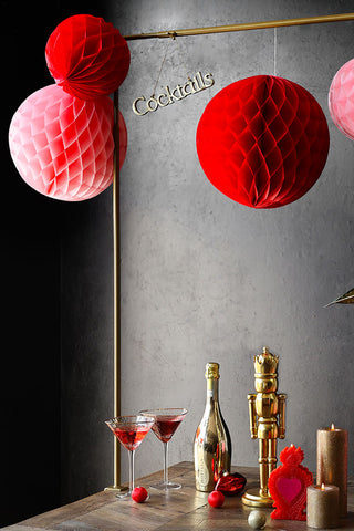 Red honeycomb decorations hanging from a gold clamp on stand