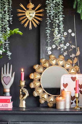 Lifestyle image of various Valentine's gifts styled on a black sideboard with greenery. 