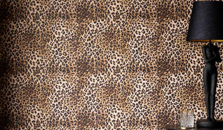 Lifestyle image of the Rockett St George Wild Leopard Love Wallpaper Roll styled with a side table, table lamp and glass. 