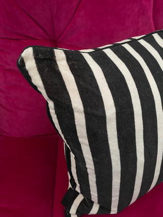 The Monochrome Striped Velvet Cushion Cover against a red background.