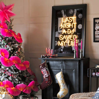 a rock n roll inspired christmas living room with a frosted snow christmas tree, last night a dj saved my life art print, stockings and pink candlesticks