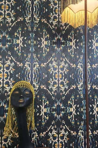 Image of Anna Hayman's Sioxsie wallpaper in blues, blacks and gold pattern with a head of a lady wearing a gold hat.