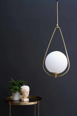 lifestyle image of globe pearl drop ceiling light with gold tray side table with plant and bust ornament with dark wall background