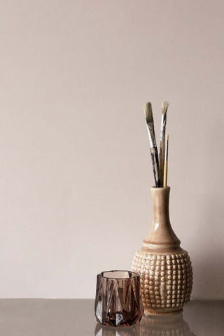 An image of a vase and tea light holder in front of a wall painted in Bohemia a warm grey colour. 