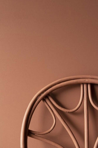 A bentwood chair painted in the same colour as the wall. The paint is a dusky pink, clay colour and is called Emanuella. 