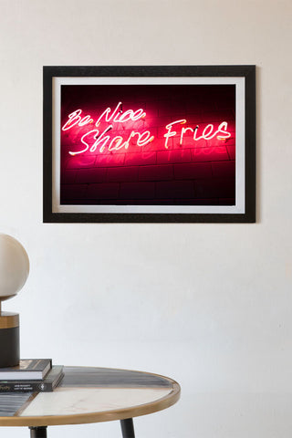 lifestyle Image of the Framed Be Nice Share Fries Neon Art Print on white wall in black frame 