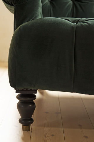 Close-up image of leg of the Two-Seater Forest Green Velvet Sofa on pale wooden floor