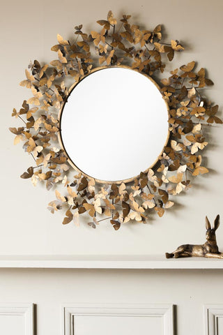 Image of the Antiqued Butterflies Round Wall Mirror hanging on a wall