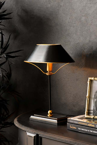 lifestyle image of black & gold table lamp with light on 