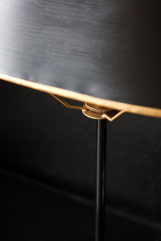 close up image of black & gold table lamp on black table 