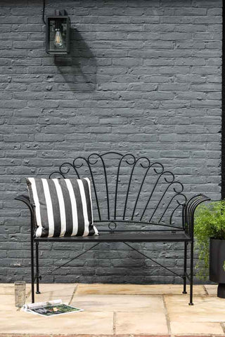 Lifestyle image of the Black Metal Garden Bench with black and white outside cushion
