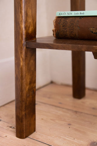 Close-up image of the bottom shelf and legs on the Dark Mango Wood Bedside Table With Cable Gap