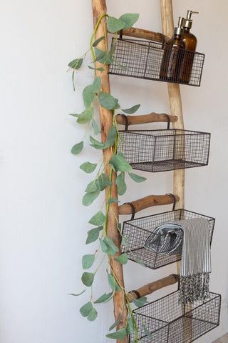 Close up image of the wooden ladder with baskets filled with soap decanters and towels.