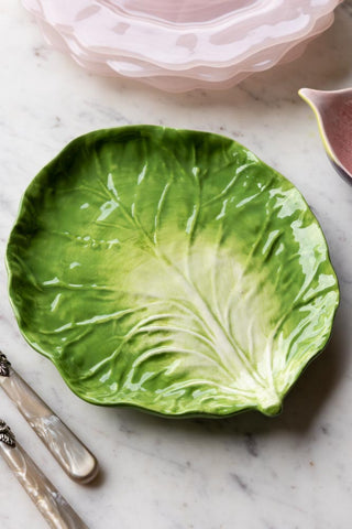 Lifestyle image of the Green Cabbage Leaf Plate with pink accessories