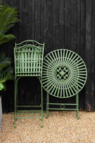 Image of the Green Metal Garden Table & Chair Set folded up against a fence
