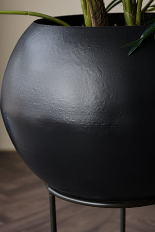 Close up detail image of iron planter on its stand with wooden flooring