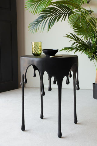 Lifestyle Image of the Matt Black Drip Side Table with green accessories