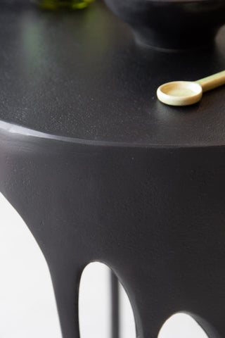 Close-up image of the table top on the Matt Black Drip Side Table with a spoon