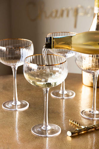 Lifestyle image of the Set Of 4 Ribbed Champagne Coupe Glasses With Gold Rim
