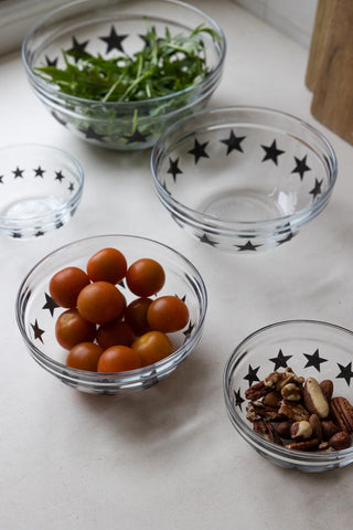Image of the black star bowls without lids. The largest bowl is filled with leafy greens