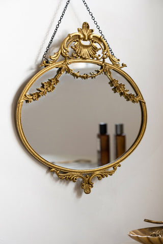 Lifestyle image of the Small Pretty Gold Hanging Mirror