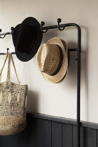 Close-up image of the coat hooks on the Industrial-Style Hallway Storage Coat Rack with hats and bag hung on hooks with pale wall background