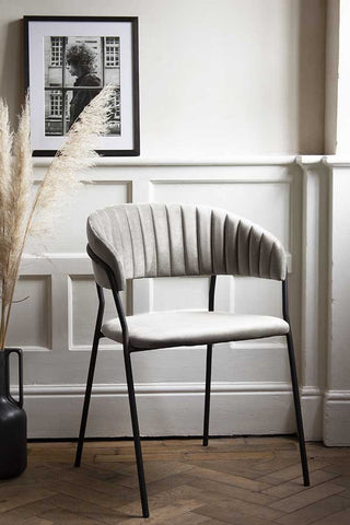 Lifestyle image of Curved Back Velvet Dining Chair In Mink Grey with panelled wall facing right