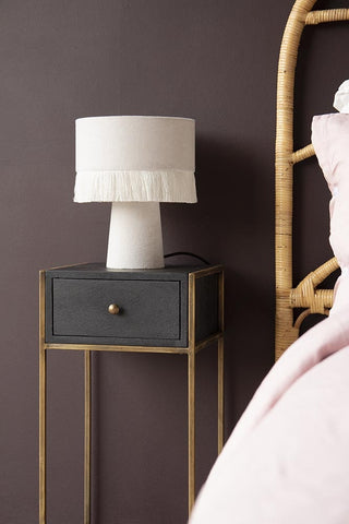 Lifestyle image of the Sophos Single Drawer Bedside Table next to a bed with a lamp on top with dark wall background