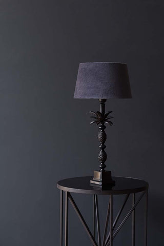 A black table lamp on a black table photographed in front of a wall painted in Portobello, a Rockett St George paint. 