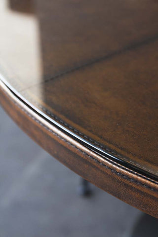 Close up image of the leather top dining table. The table has a glass top to protect the leather finish. 