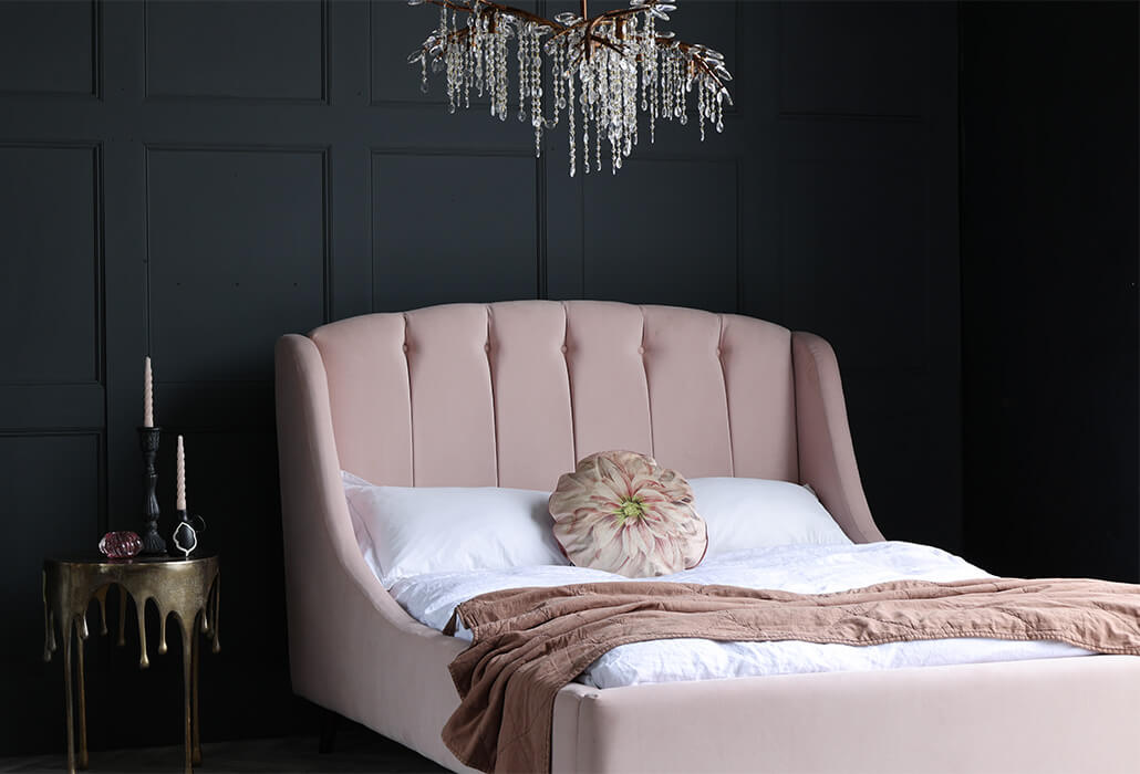 pink double bed, gold drip table and chandelier above bed